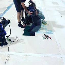 man clearing drain in swimming pool