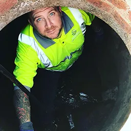 a man looking up from a drain